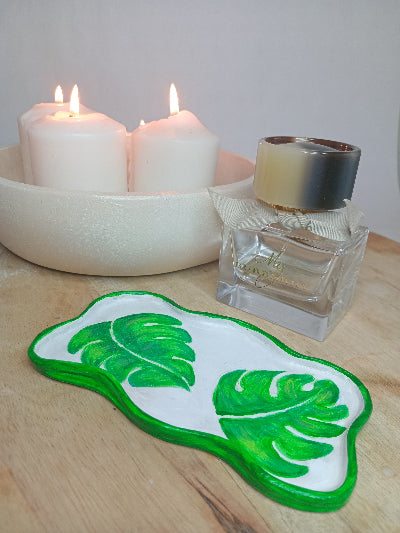 Rose gold watch on a Green monstera leafed clay trinket tray on a wooden board with candles