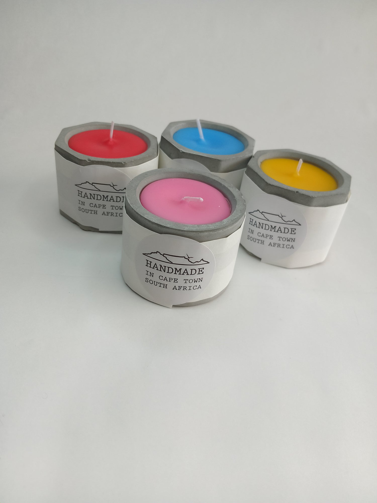 Four colorful candles in concrete casted holders on a white background