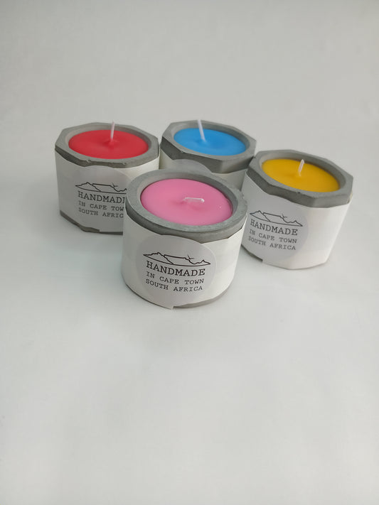 Four colorful candles in concrete casted holders on a white background
