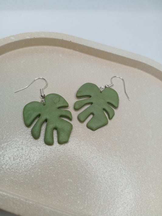 Green leaf-shaped earrings on a light gray background