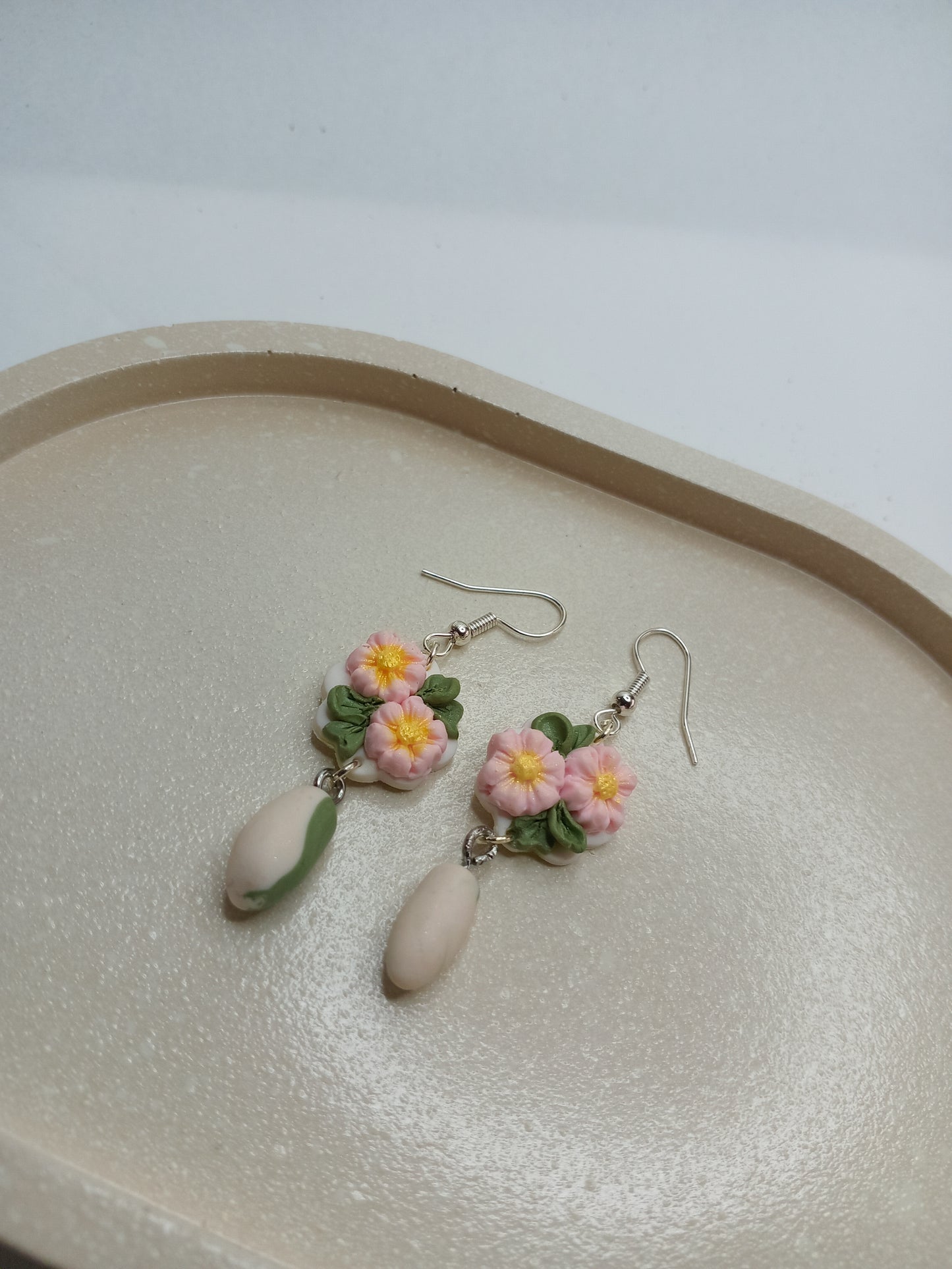 Floral earrings on a beige oval trinket dish