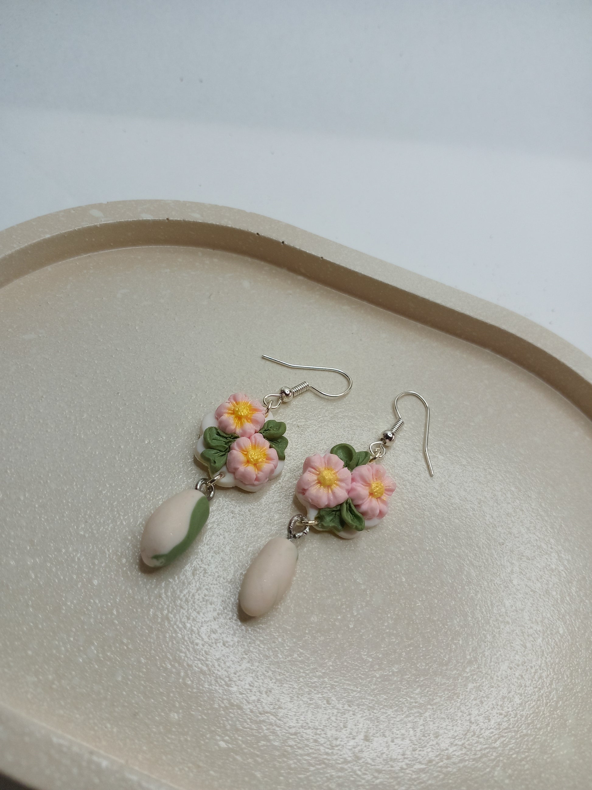 Floral earrings on a beige oval trinket dish