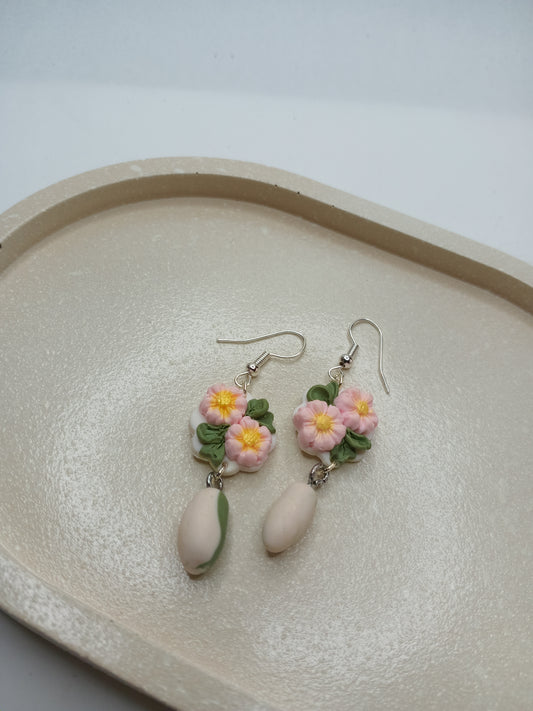 Floral earrings on a textured beige trinket dish with a white background